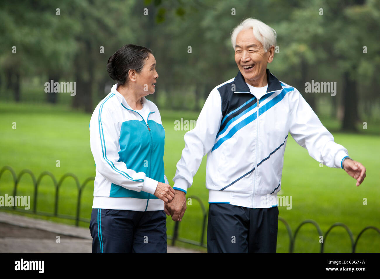 Senior Couple Walking Hand-In-Hand Through a Park Stock Photo - Alamy