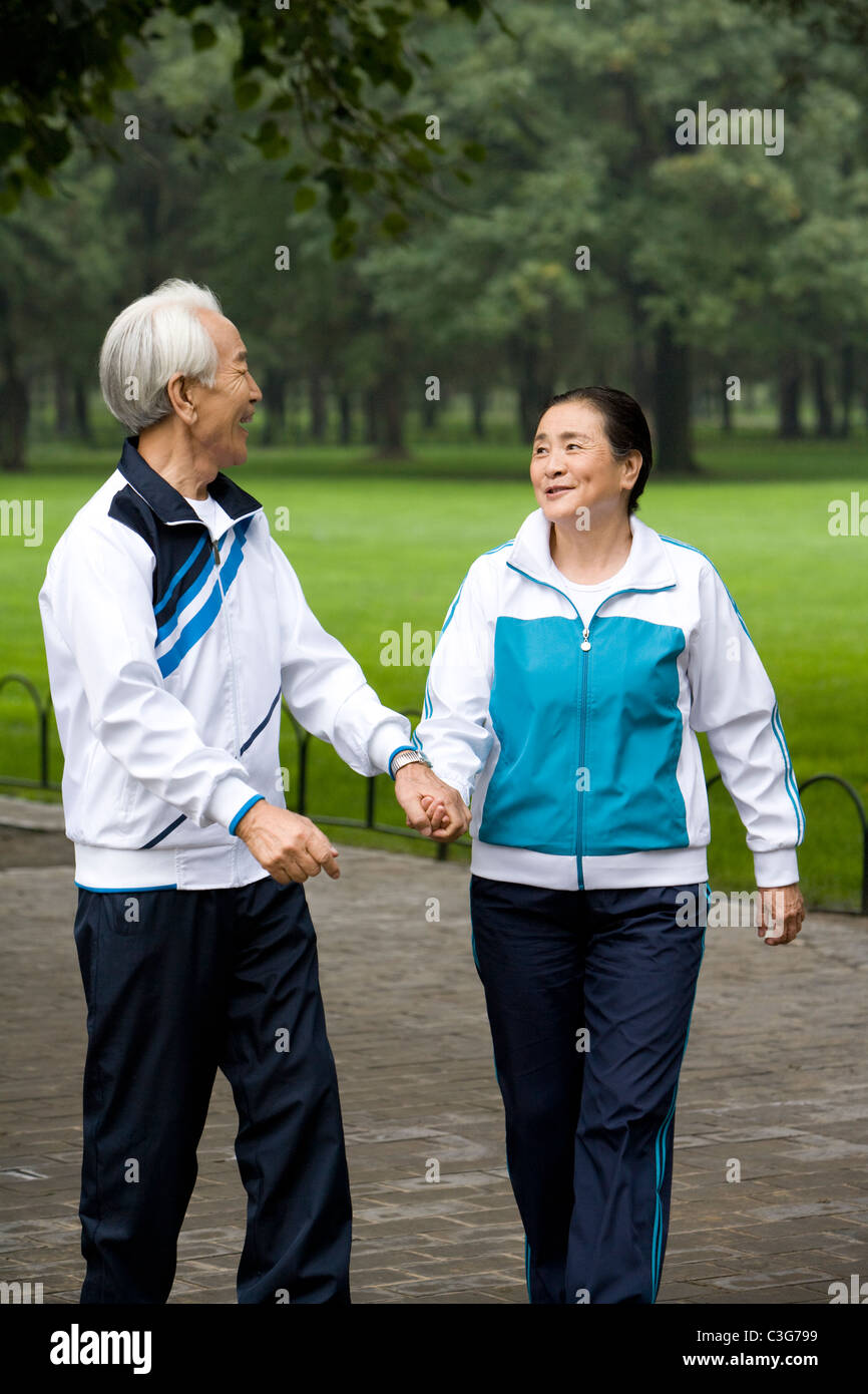 Senior Couple Walking Hand-In-Hand Through a Park Stock Photo - Alamy