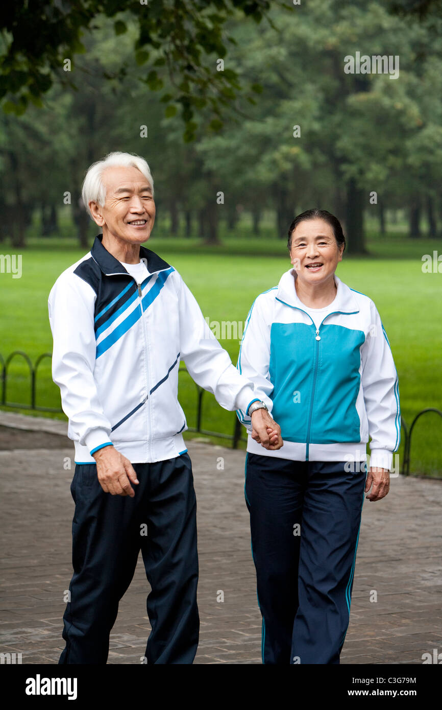 Senior Couple Walking Hand-In-Hand Through a Park Stock Photo - Alamy