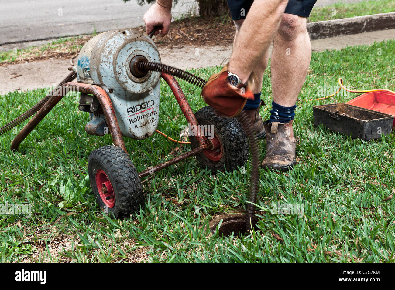A plumber using an electric eel to clear a blocked sewage line Stock