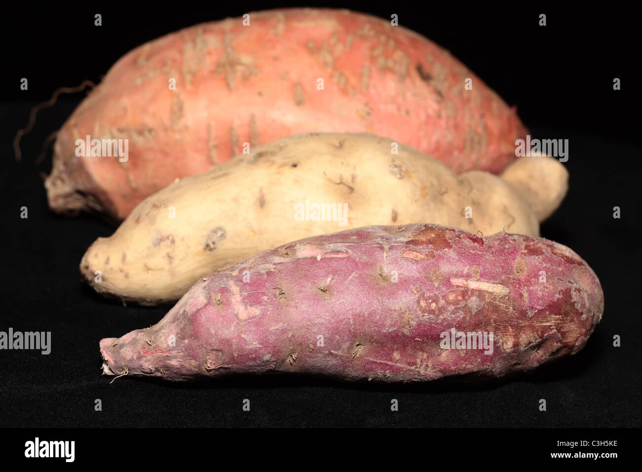 Closeup of Three Kinds of Sweet Potatoes on Black Background Stock Photo