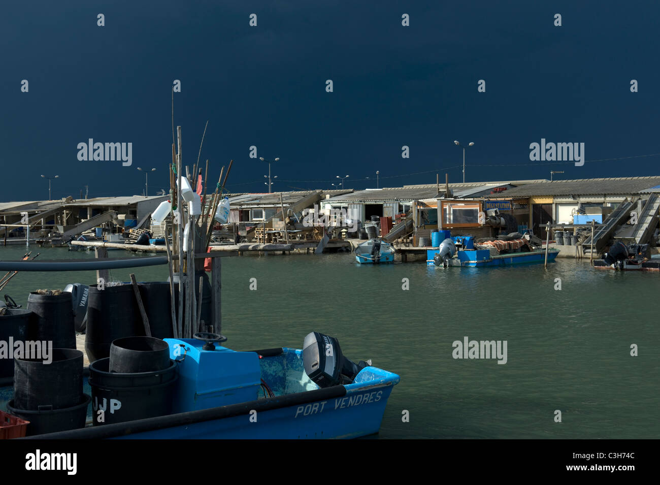 Boats and huts of oyster cultivators in the port of Les Bacarès in the Pyrénées-Orientales of Occitanie before storm Stock Photo
