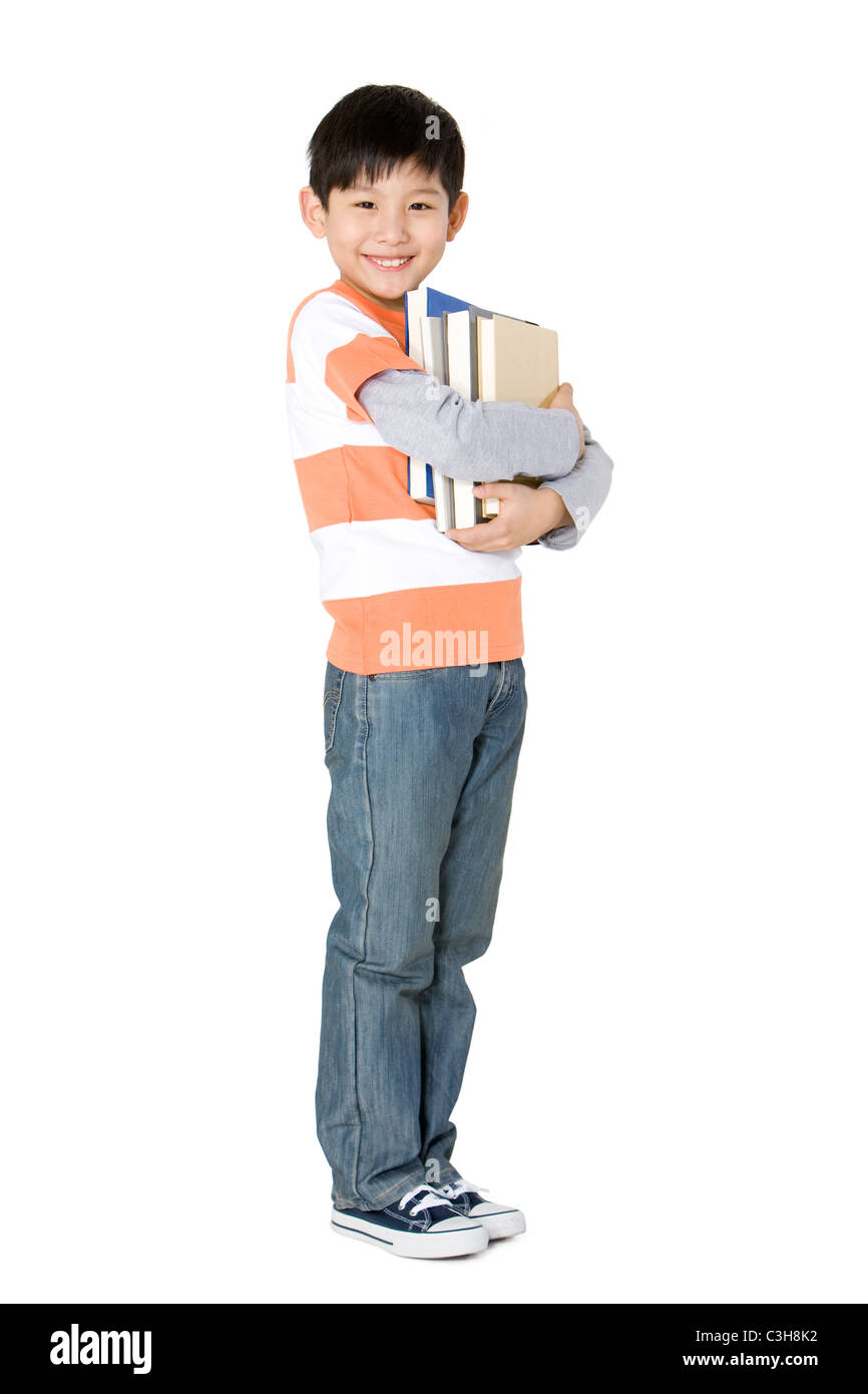 Happy young boy carrying a stack of books Stock Photo - Alamy