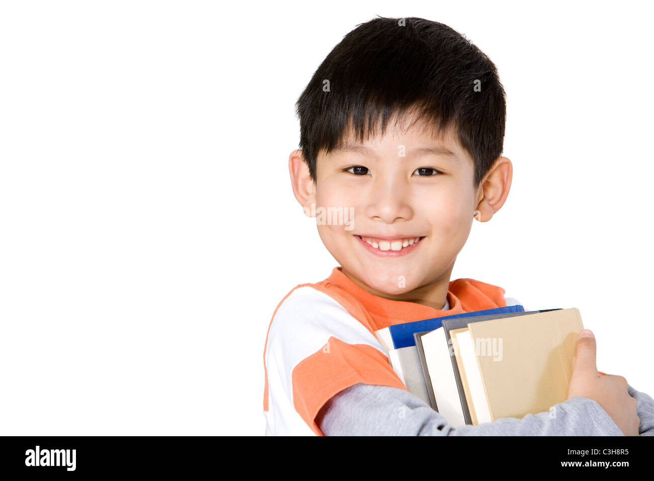 Happy young boy carrying a stack of books Stock Photo - Alamy