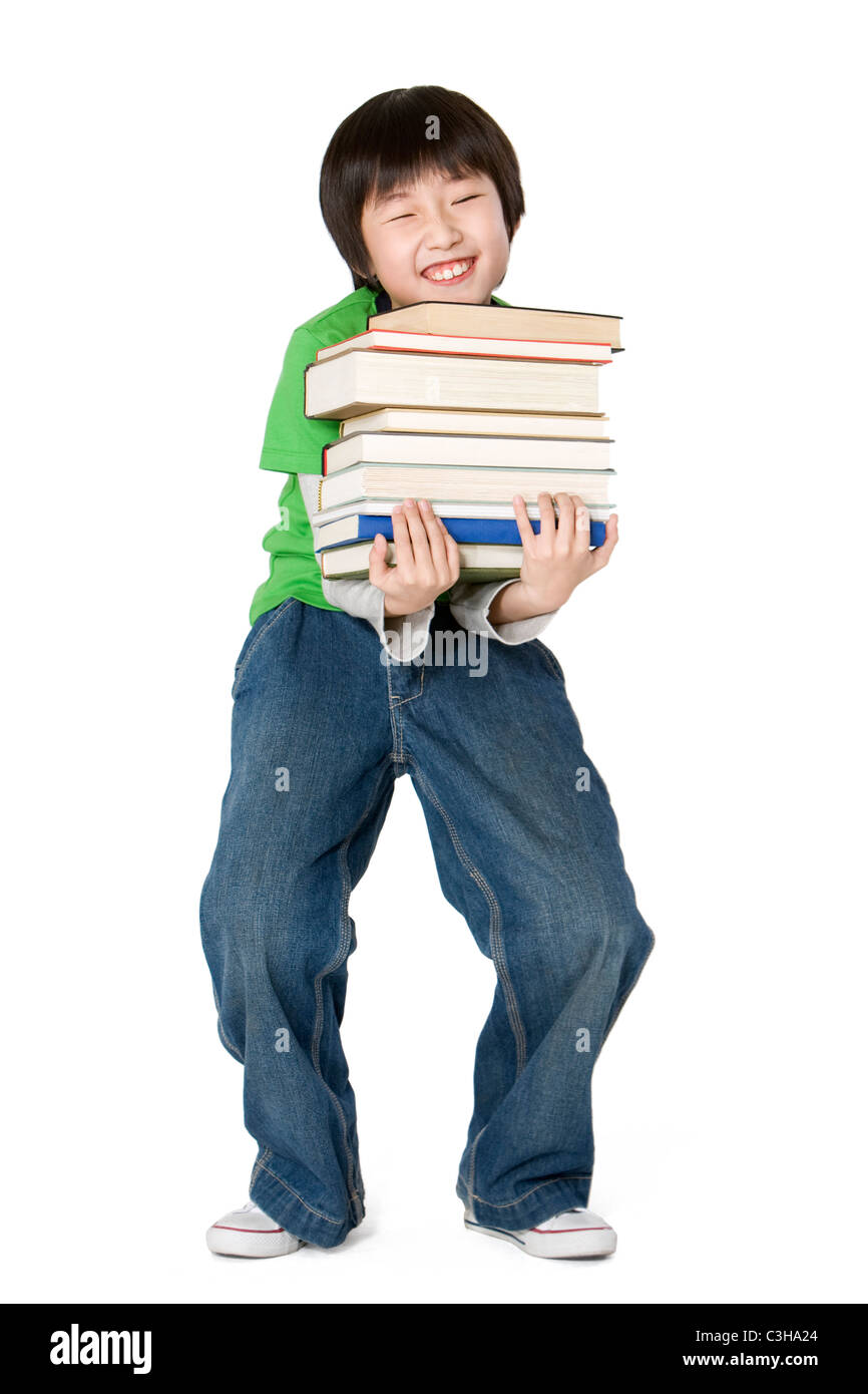 Young boy carrying a large stack of books Stock Photo - Alamy