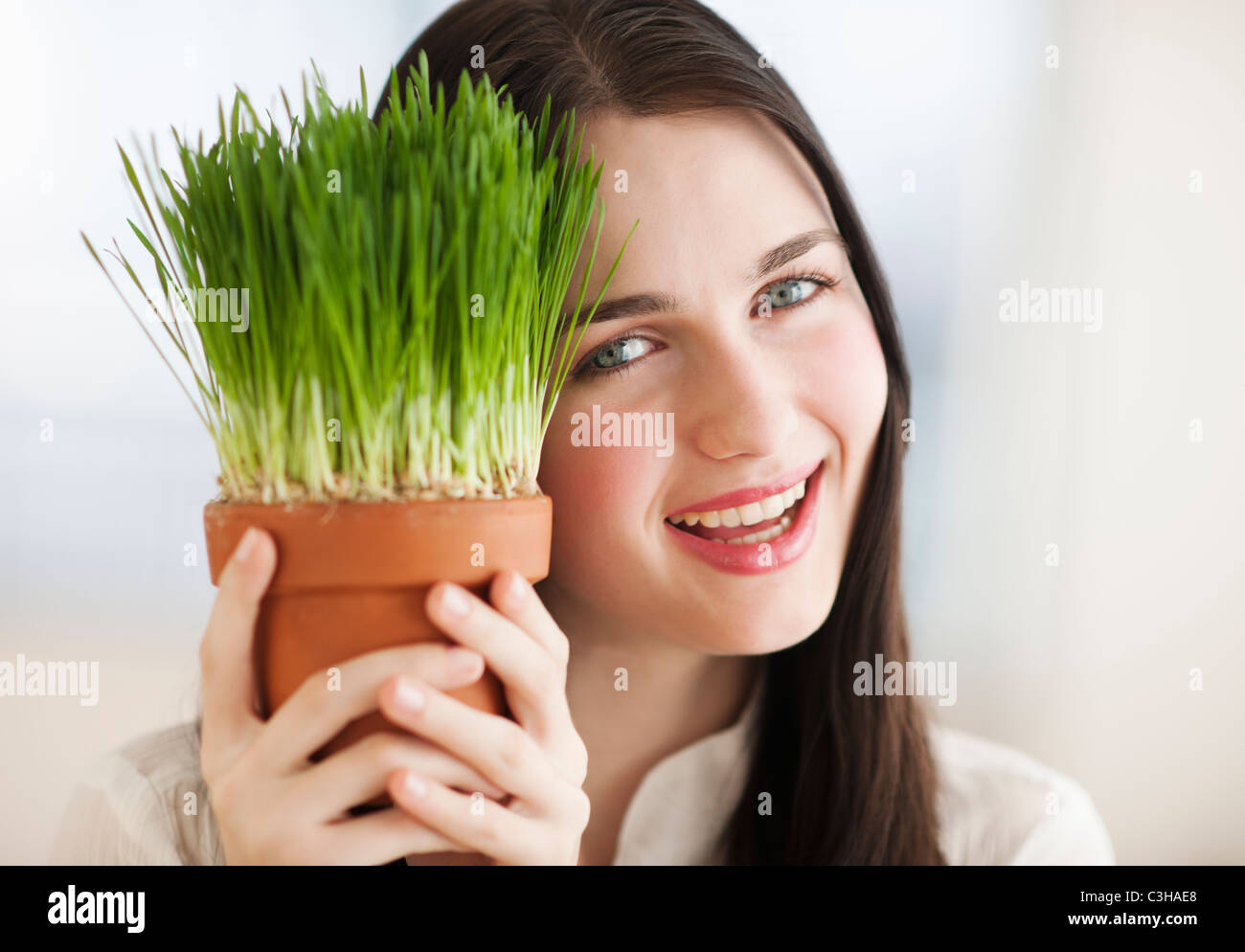 Portrait of smiling young woman holding green plant Stock Photo - Alamy
