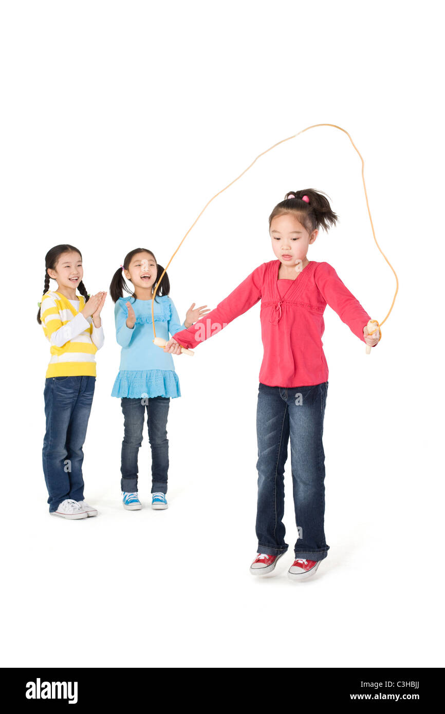 Two girls cheering their friend as she jump ropes Stock Photo Alamy