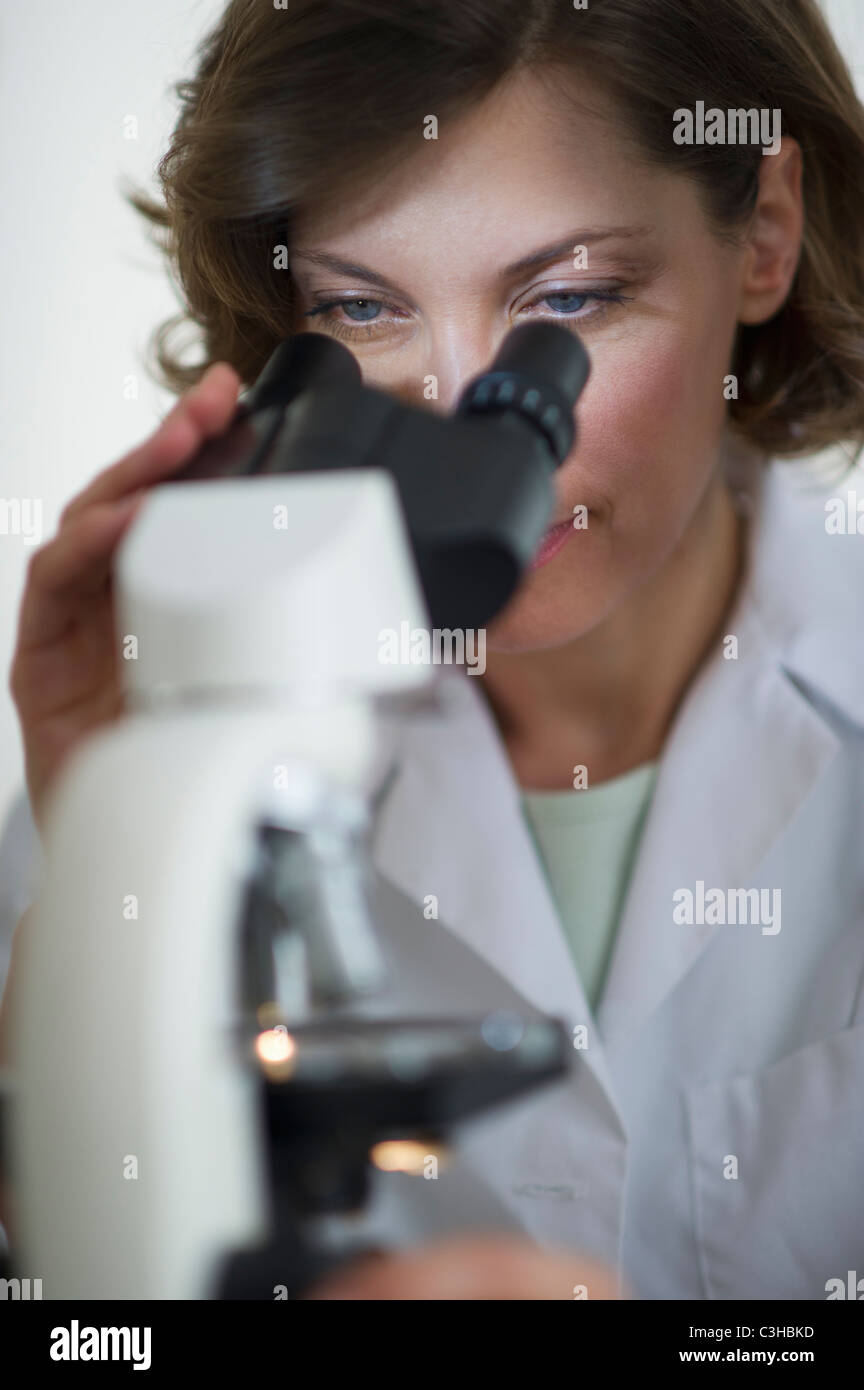 Woman in laboratory looking through microscope Stock Photo