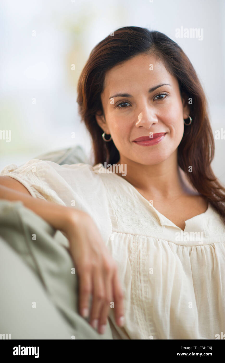 Portrait of smiling woman sitting on sofa Stock Photo - Alamy