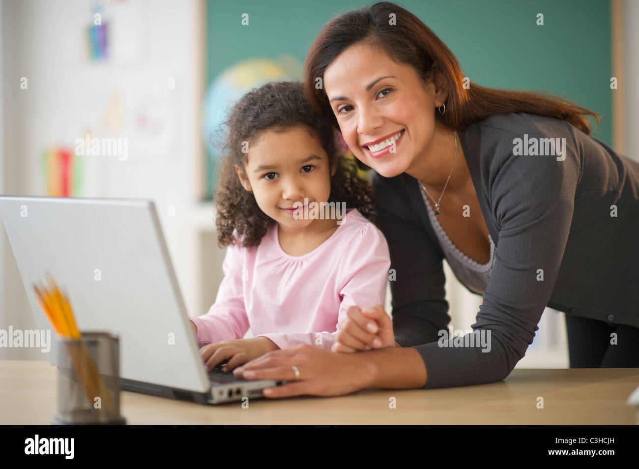 Girl (6-7) with female teacher using laptop in classroom Stock Photo ...