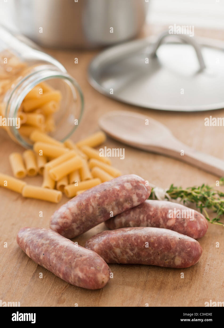 Raw sausage and pasta on kitchen table Stock Photo