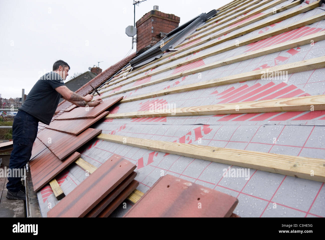 Man Nailing New House Roof Tiles Standing on Scaffolding, Re Roofing