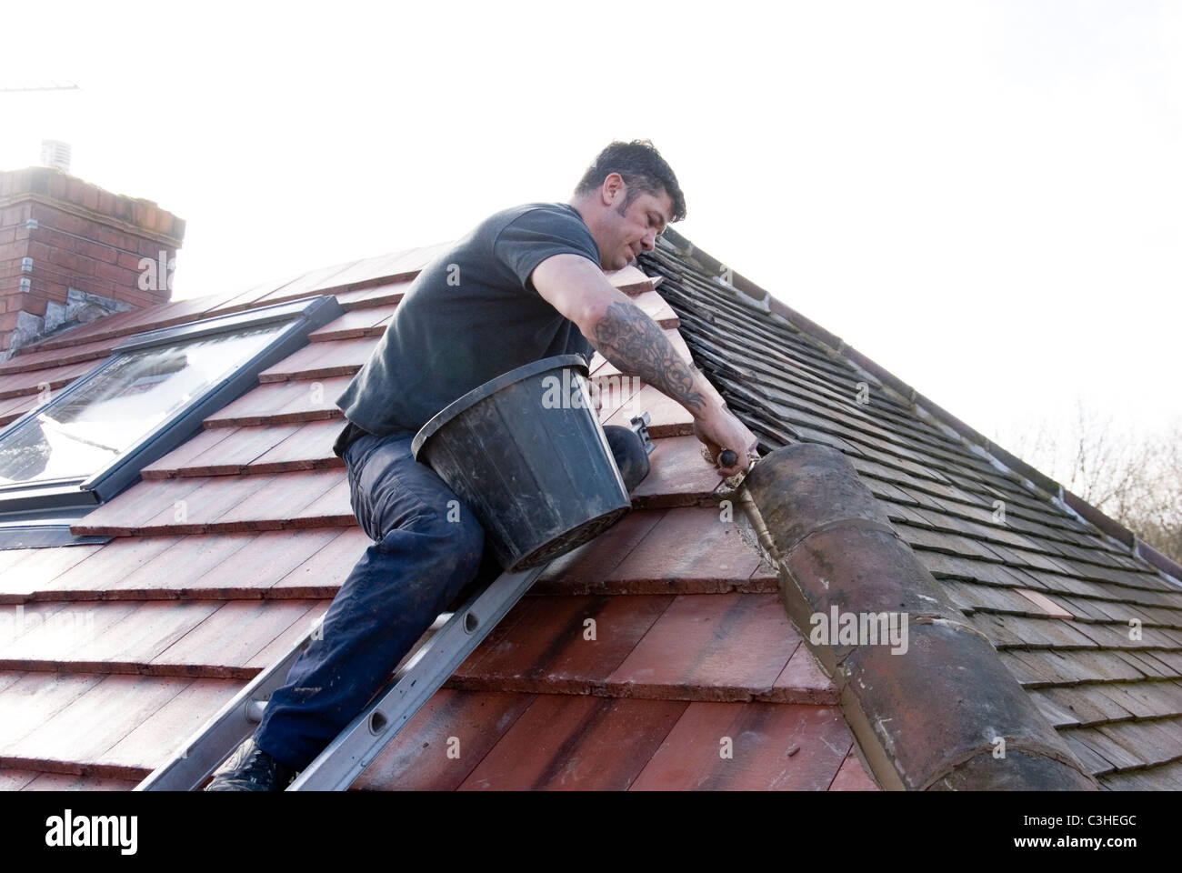 Roofer Laying Ridge Tiles with Mortar Completing Re Roofing Residential