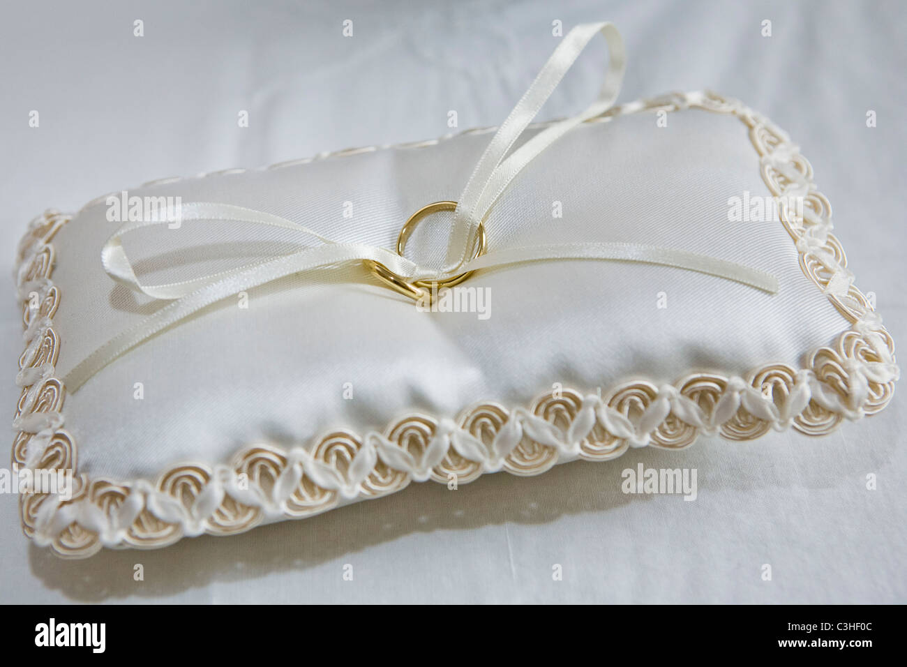 Wedding rings white embroidered cushion close up Stock Photo Alamy