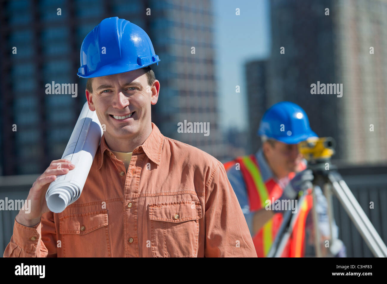 Portrait of construction worker holding rolled up blueprint Stock Photo ...