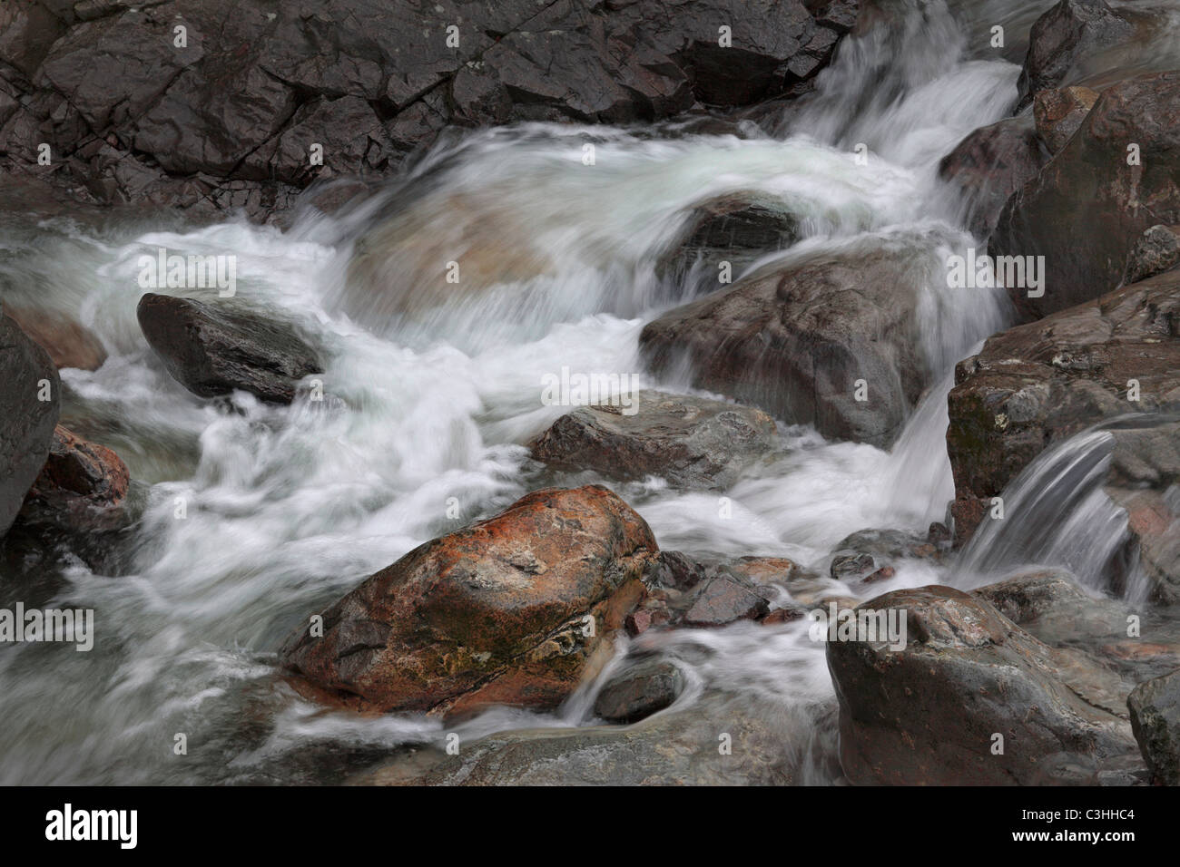 An energetic cascade of water flows through rocks in the river near Seatoller in the Lake District of England Stock Photo