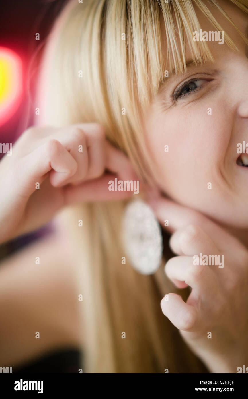 Young woman putting on earring Stock Photo