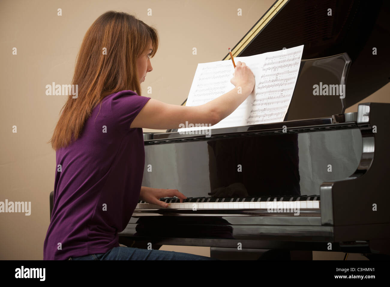 Young woman marking score before setting to play grand piano Stock Photo