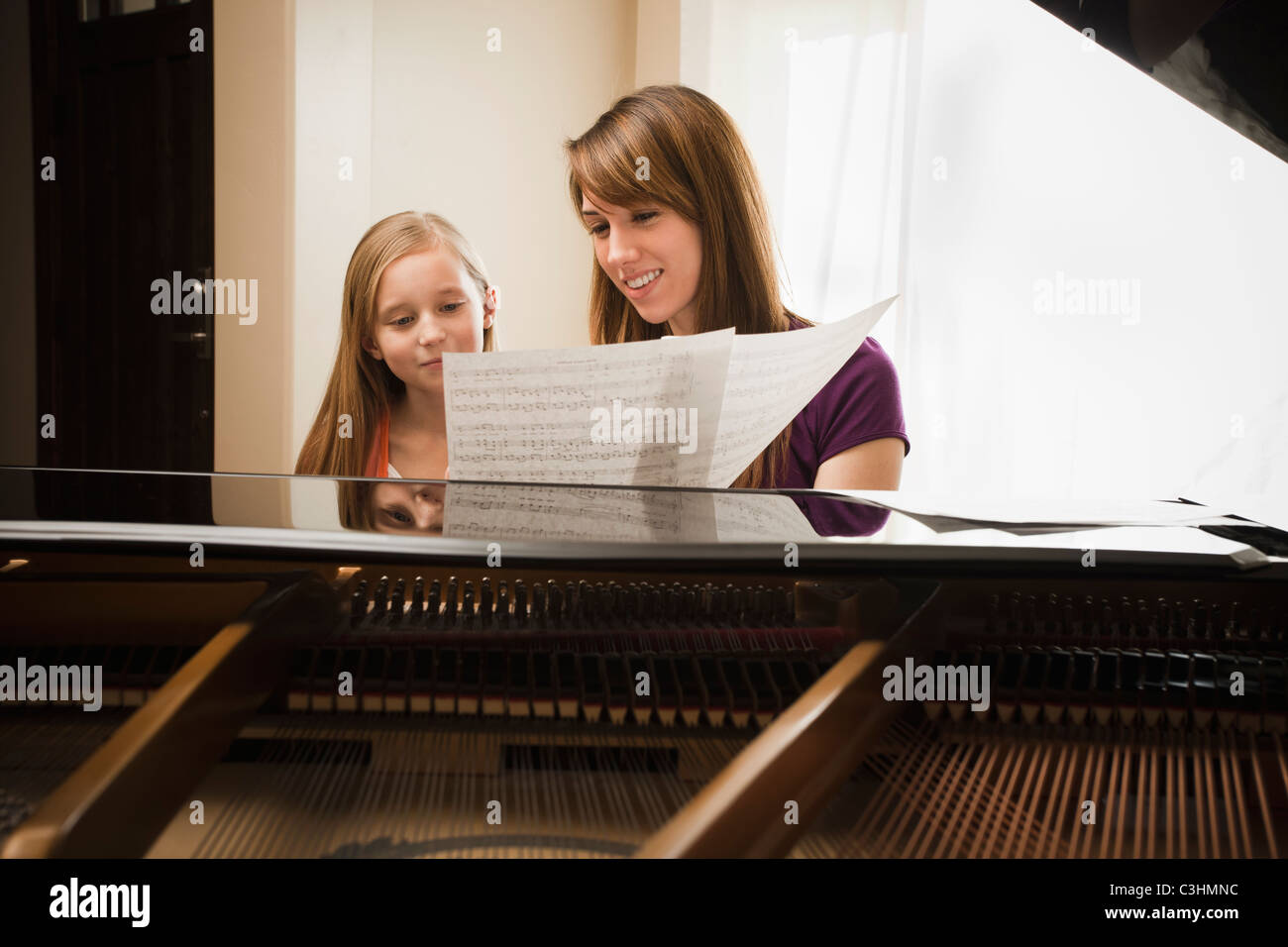 Girl (8-9) assisting mother with music score Stock Photo