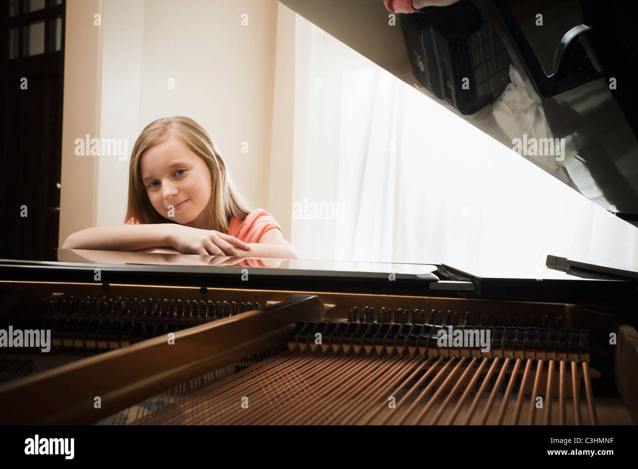 Girl (8-9) leaning on grand piano Stock Photo