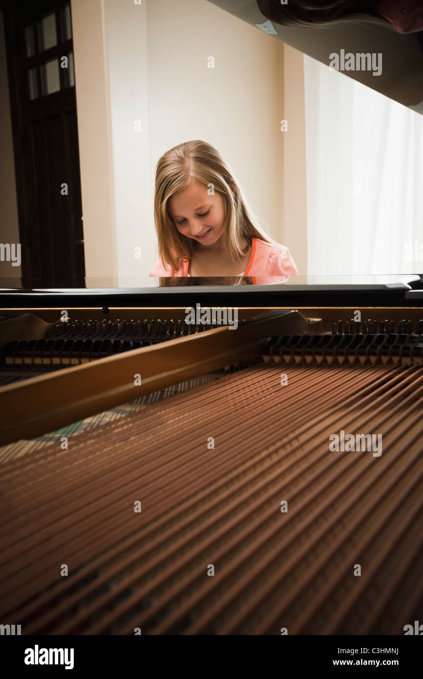 Girl (8-9) playing on grand piano Stock Photo