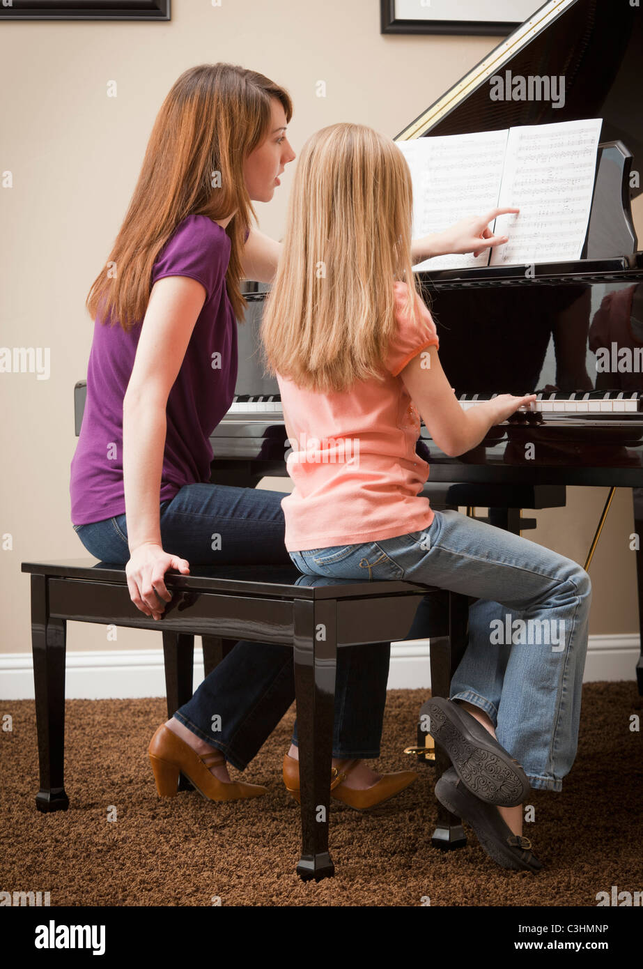 Girl (8-9) and mother playing grand piano Stock Photo