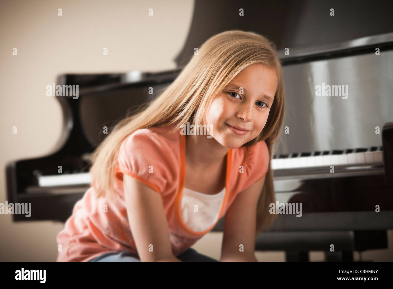 Portrait of girl (8-9) sitting by piano Stock Photo
