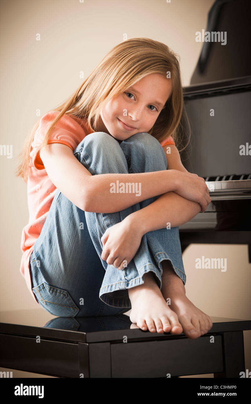 Portrait of girl (8-9) sitting by piano Stock Photo