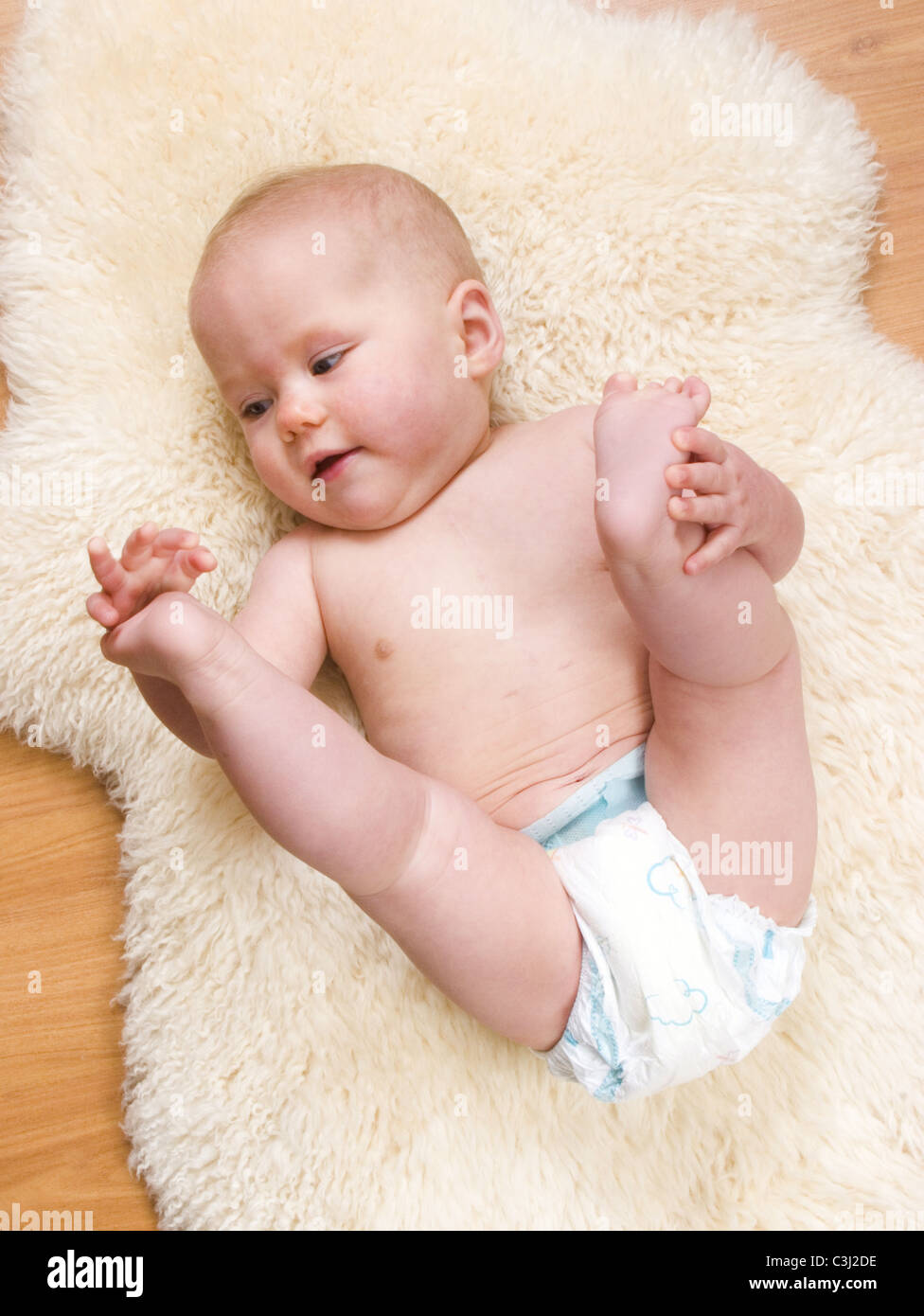Baby in nappy diaper playing with feet Stock Photo Alamy
