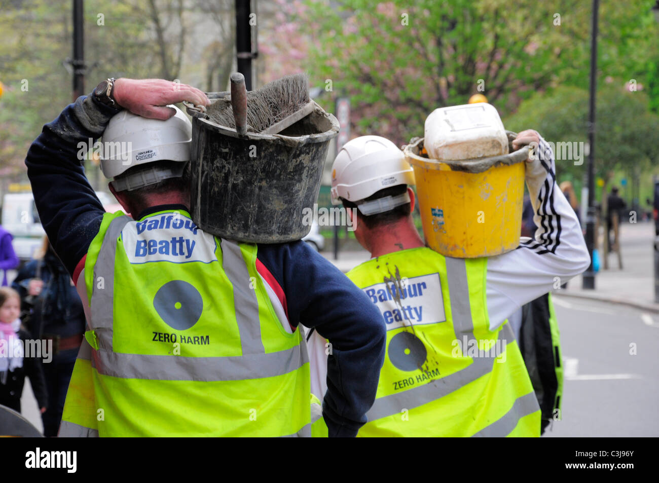 Construction workers with tools in London street walking to site Stock