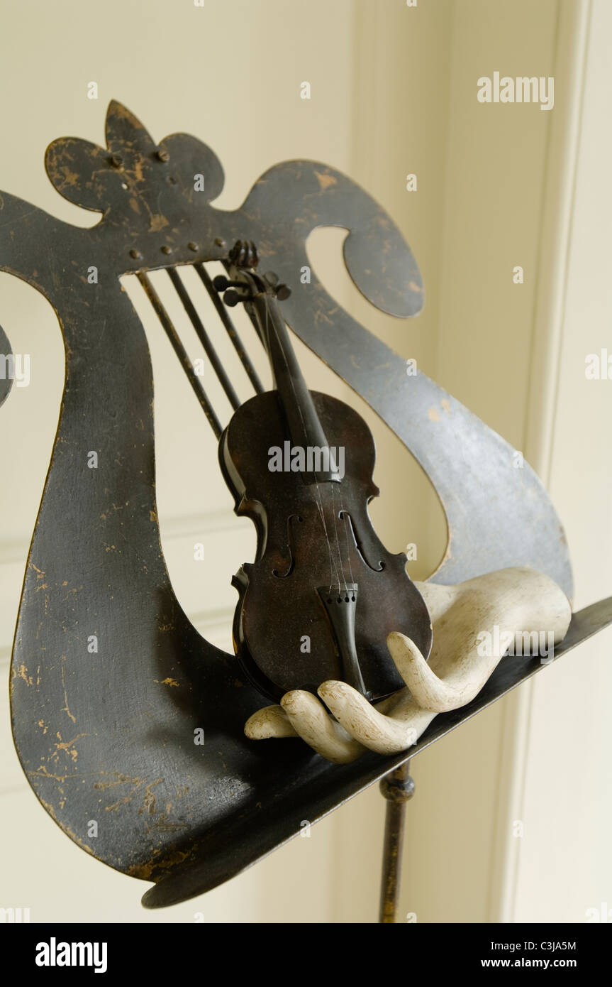 F hole music stand with small violin and hand sculpture Stock