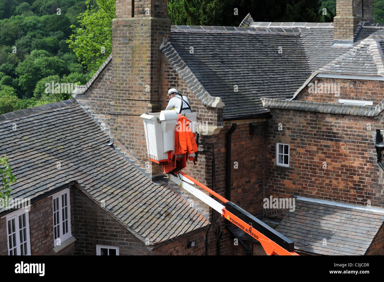 Electrical conractor repalcing old external cables on old house UK Stock Photo