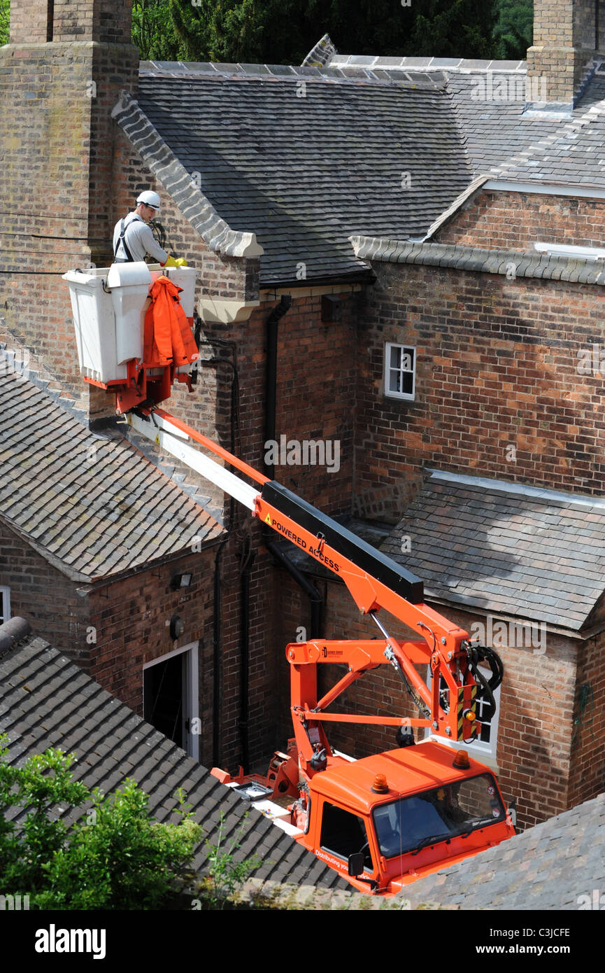 Electrical contractor replacing old external cables on old house UK Stock Photo