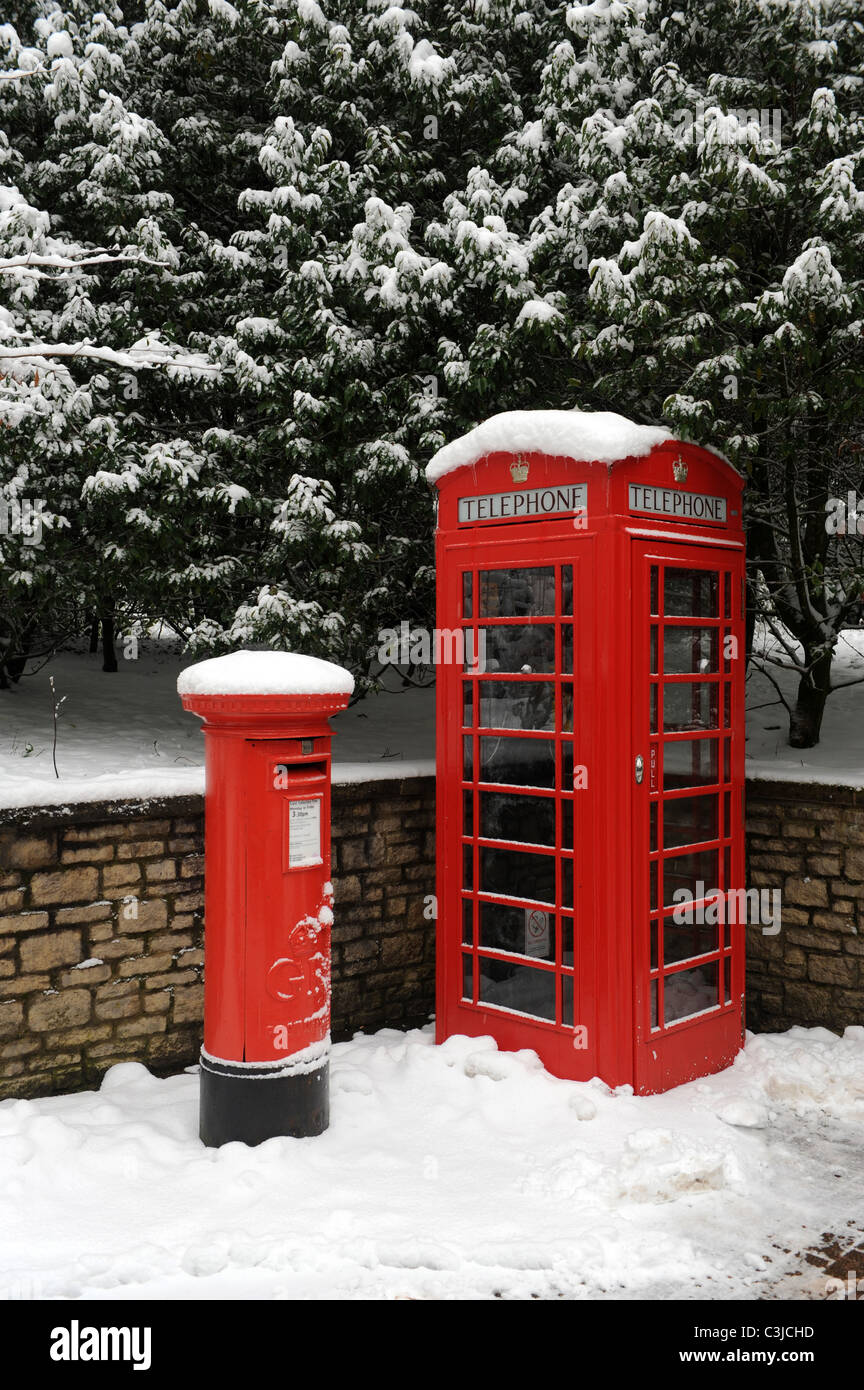 Red mailbox and phone box in the snow England Uk Stock Photo