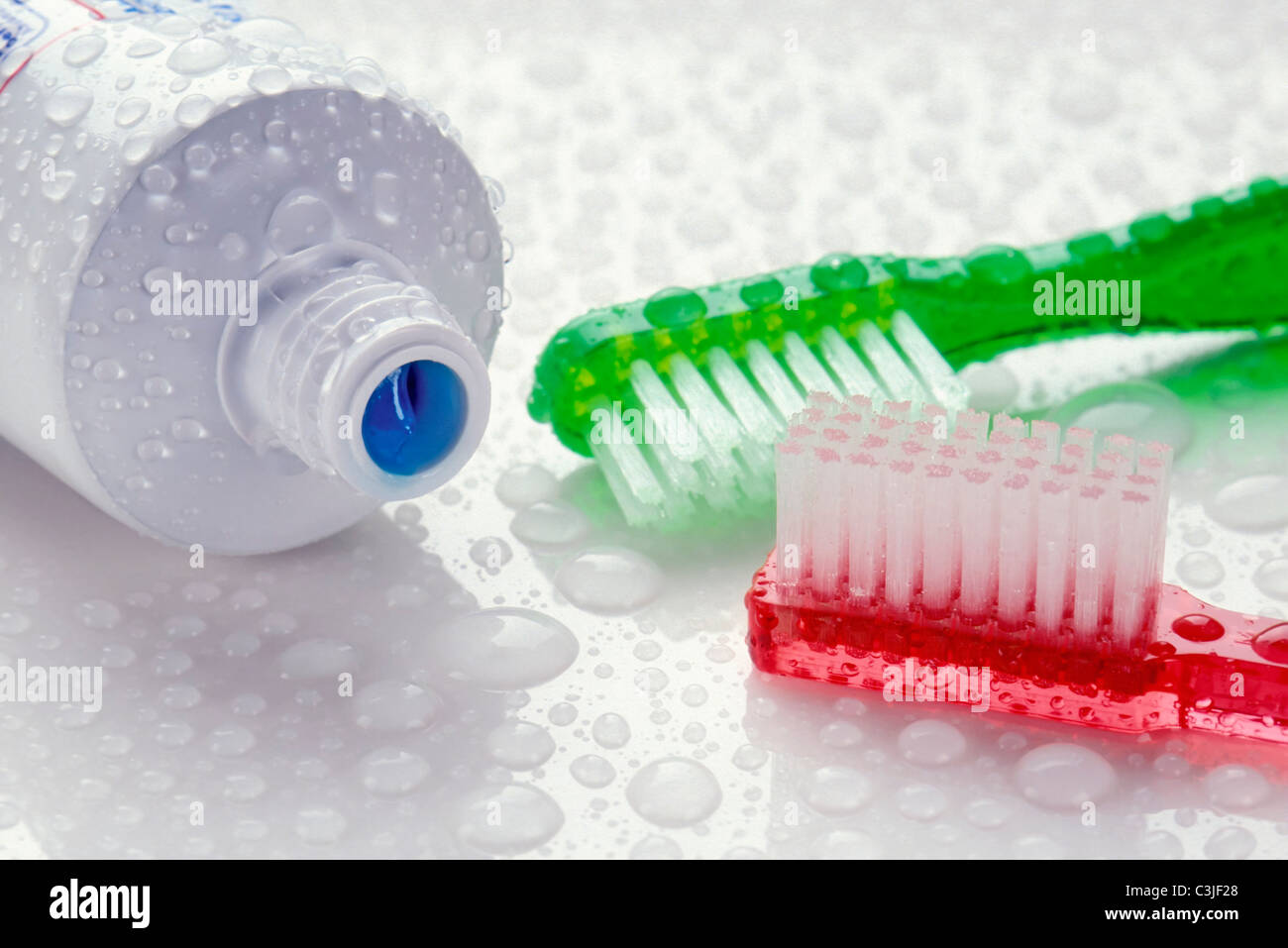 Closeup of toothpaste and toothbrushes covered with water drops Stock