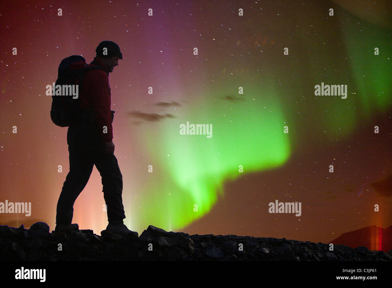 The Northern Lights or Aurora Borealis over Iceland's south Coast, at Skaftafell and a silhouetted walker Stock Photo