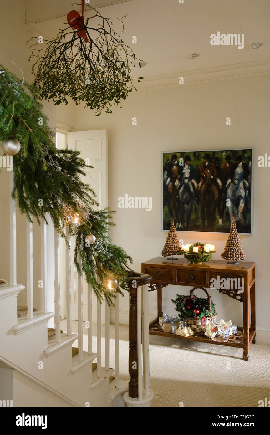 Festive decorated entrance hall with mistletoe, candlelit console table and pine garland Stock Photo