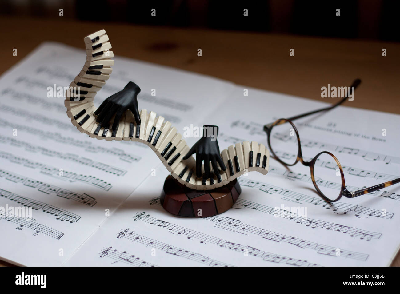 Black hands playing piano with sheet music and antique spectacles Stock Photo