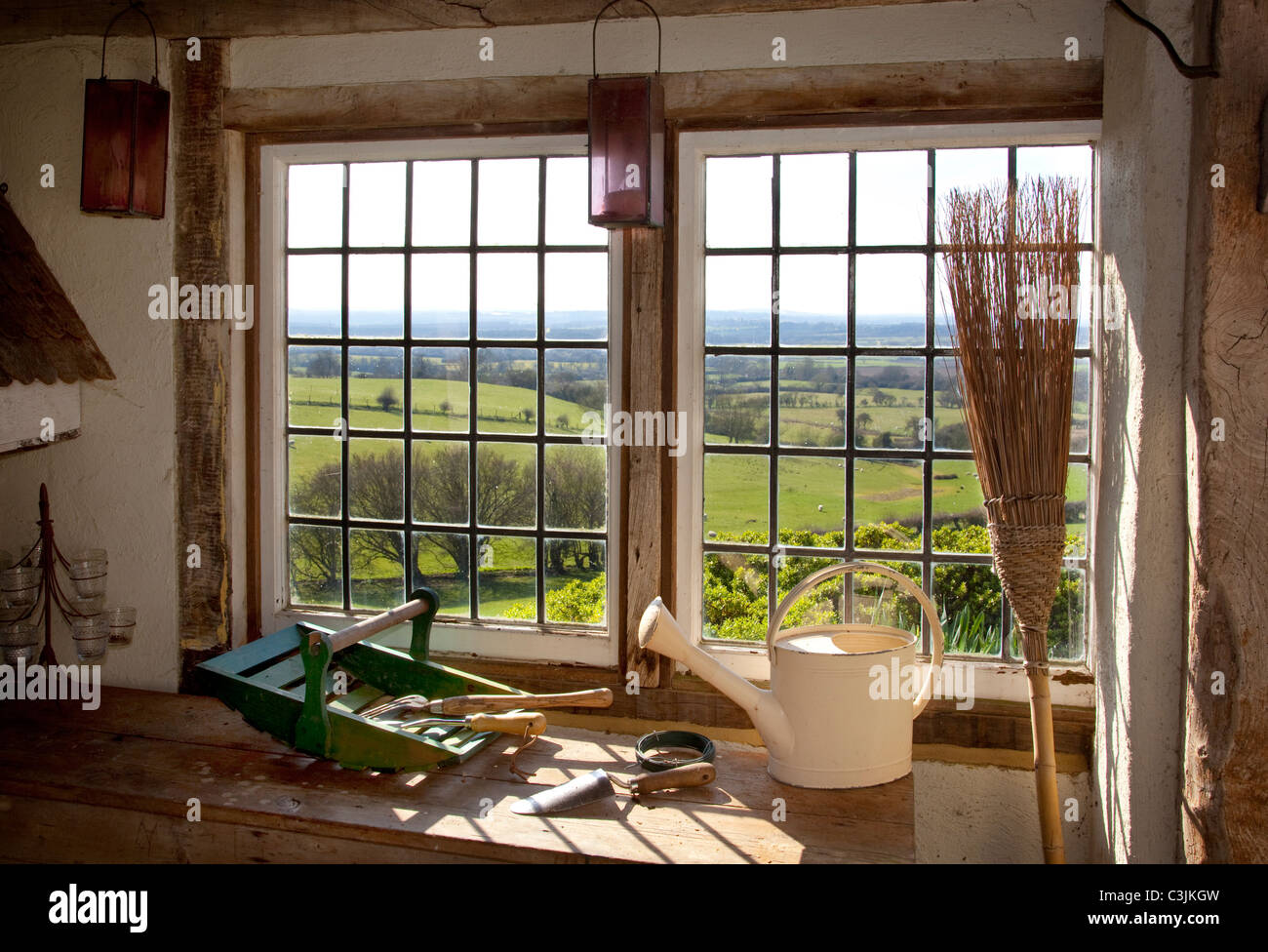 Wooden potting shed with view through metal framed windows,with garden tools,broom,watering can and wood trug basket on wood top Stock Photo