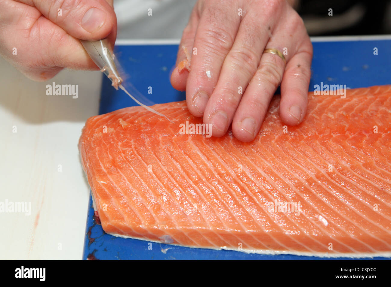 A chef Pinboning a fresh fillet of Scottish salmon. Removing fine bones