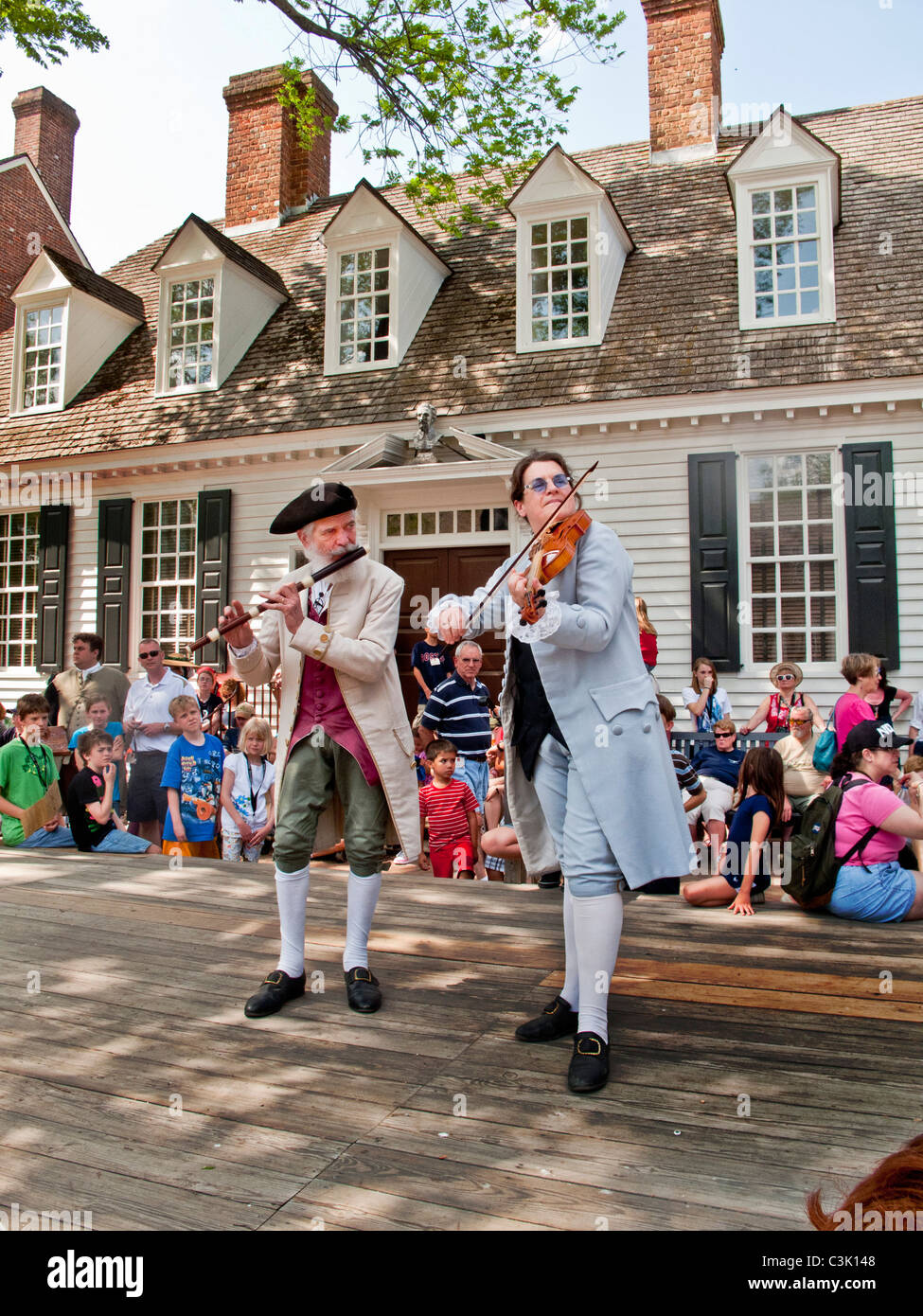 Wearing historic costumes, musicians play fiddle and flute outside the Raleigh Tavern in Colonial Williamsburg, VA. Stock Photo