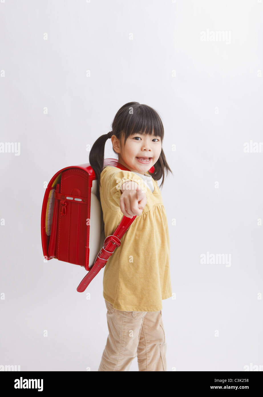 Girl with school bag pointing Stock Photo