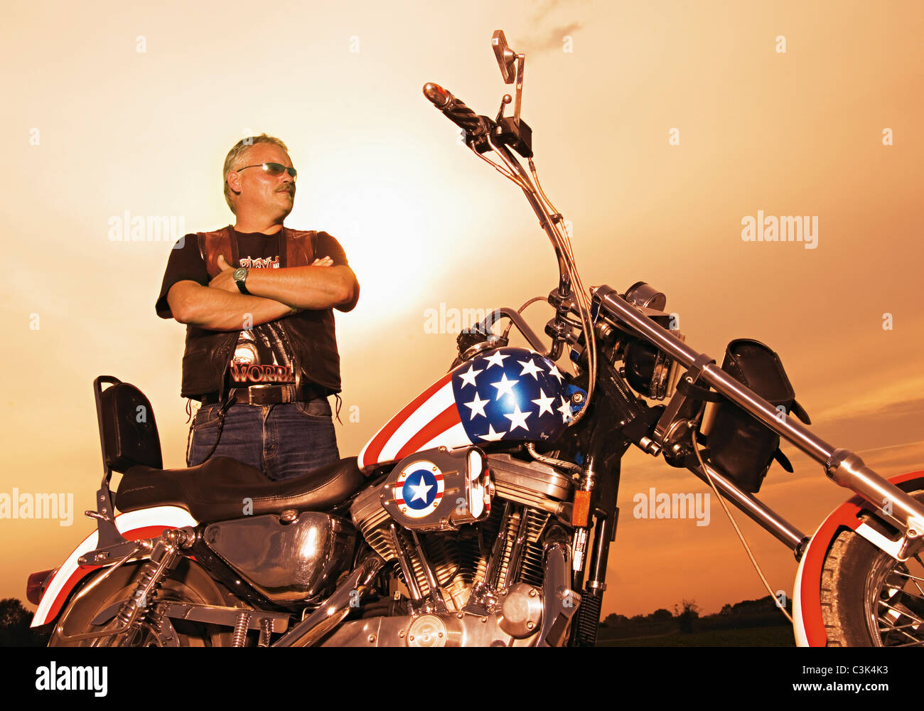 Germany, Mature motorcyclist with motorcycle at dusk Stock Photo