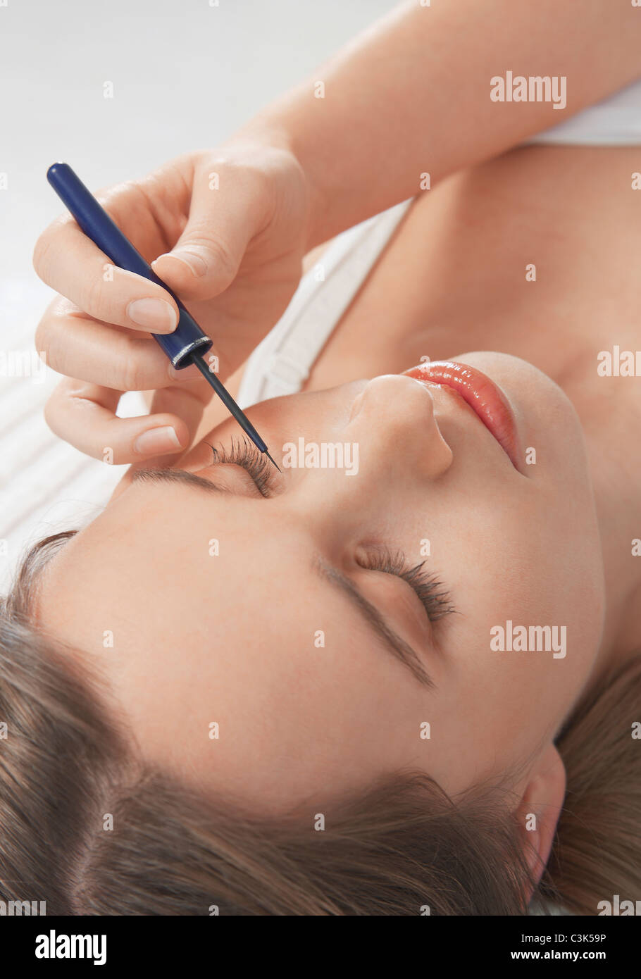 Human hand applying eye liner on a young woman's eyes Stock Photo
