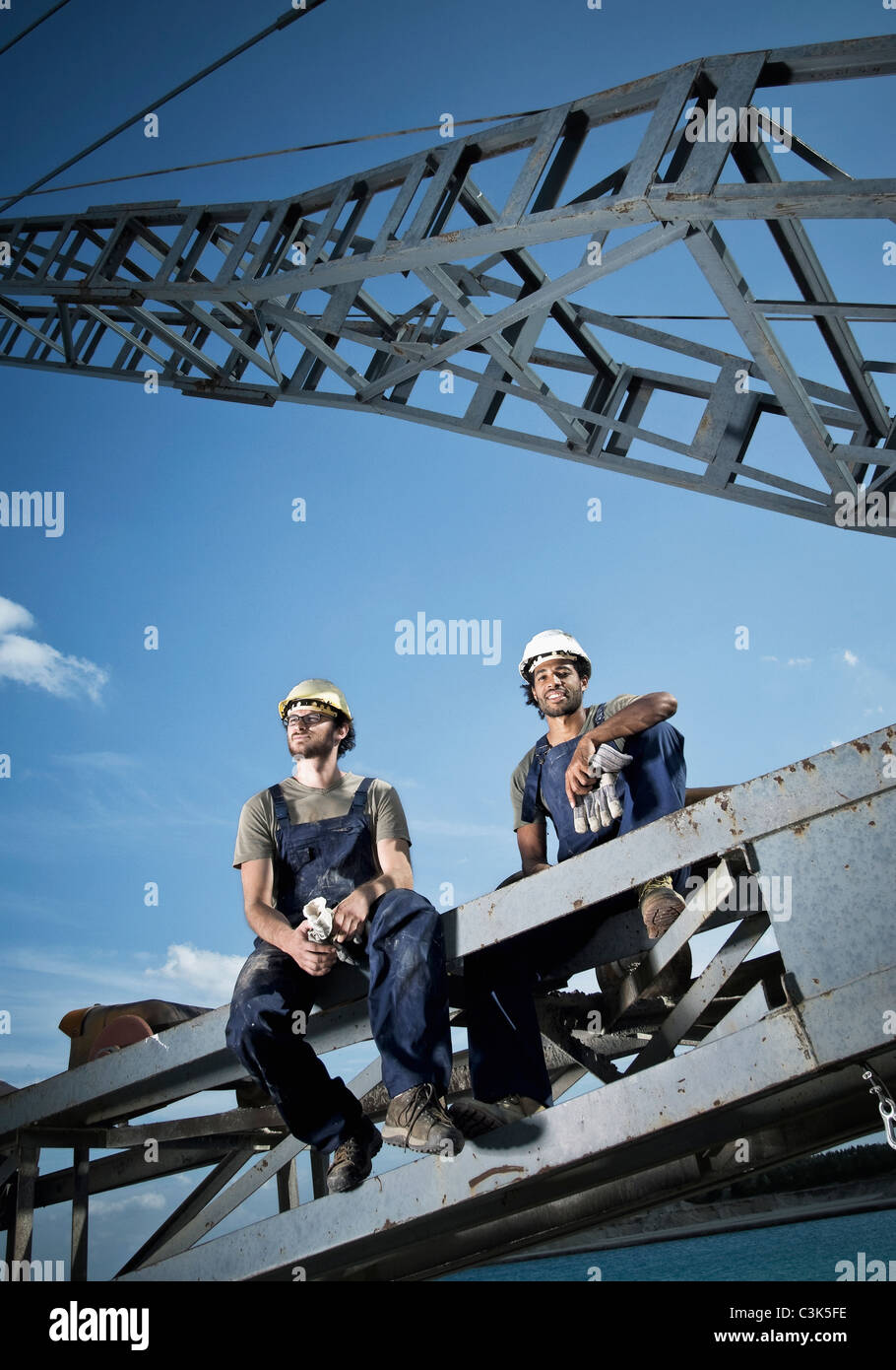 Germany, Augsburg, Two workers sitting on steel structure Stock Photo