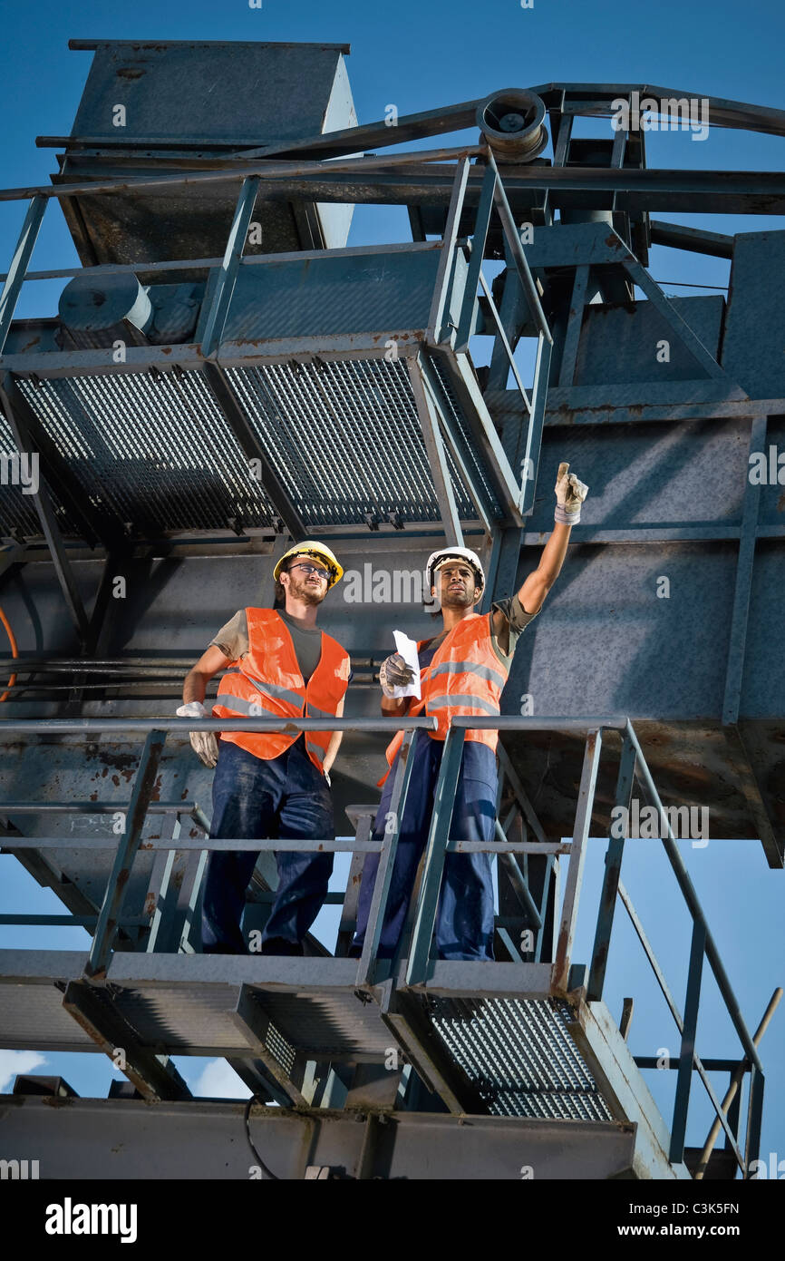 Germany, Augsburg, Two workers standing on large machine Stock Photo