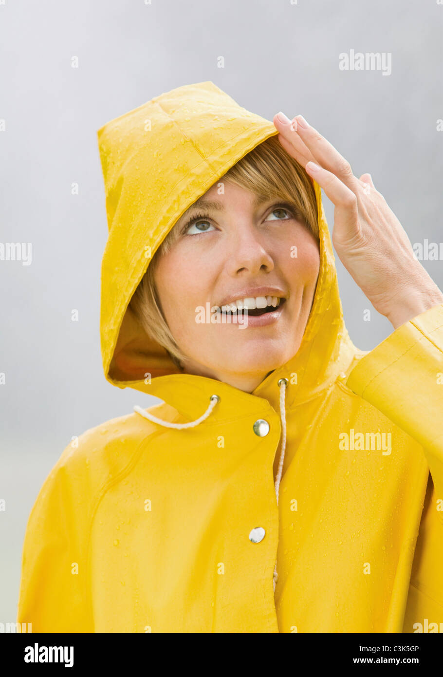 Woman in yellow rain coat looking up and smiling Stock Photo Alamy