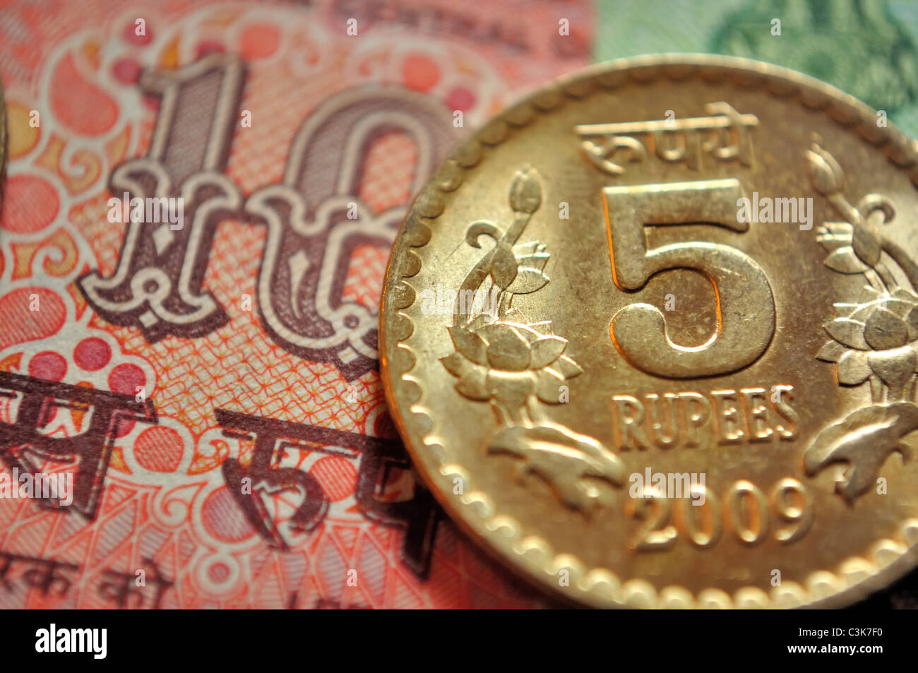 Indian currency, a coin of Rs. 5 and in the background a note of Rs. 10 Stock Photo