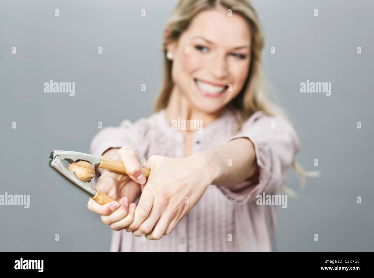 Mid adult woman cracking walnut with nut cracker Stock Photo