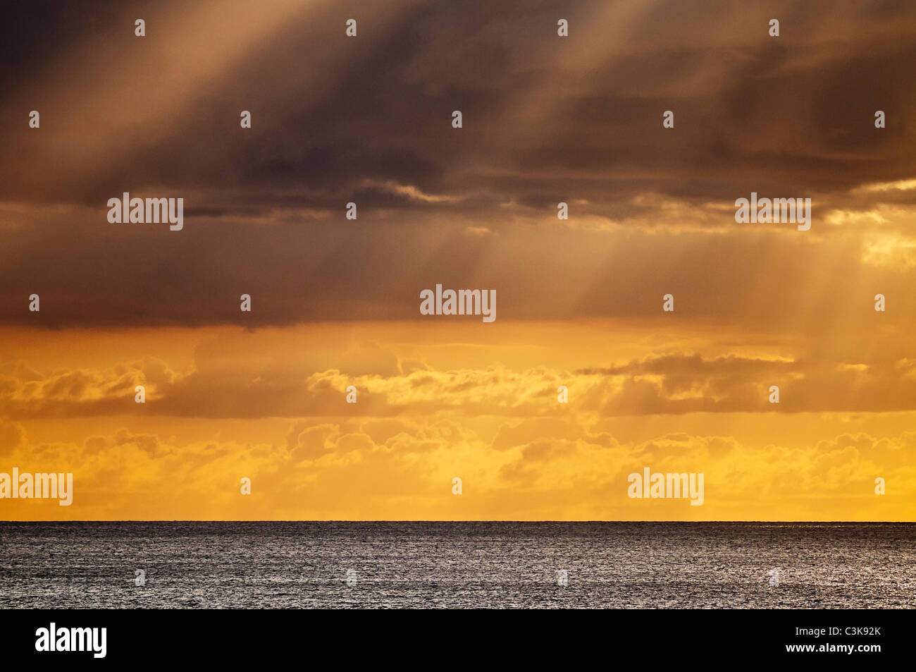 A colorful golden sunset with clouds off of Waikiki beach, Honolulu, Hawaii. Stock Photo